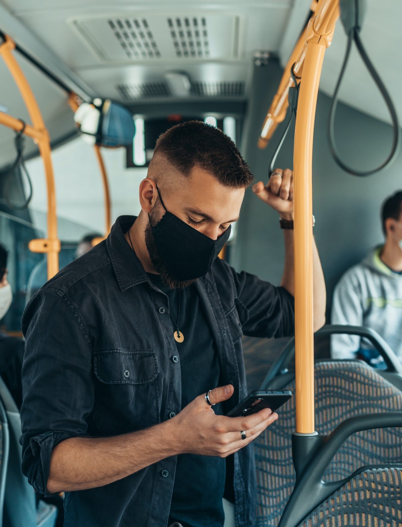 man-wearing-a-protective-mask-and-using-a-smartphone-while-keeping-the-distance-in-the-bus.jpg